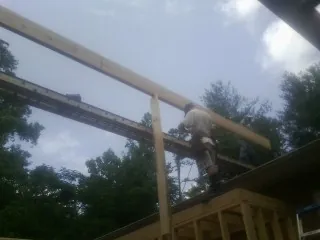 Carpenter setting a ridge beam over a new addition frame — Ice Dam Removal by Roofing Brothers in Pentwater