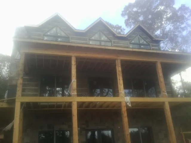 Dormers and porch framing on a large log home under construction — Roof Coating work by our crew in Pentwater