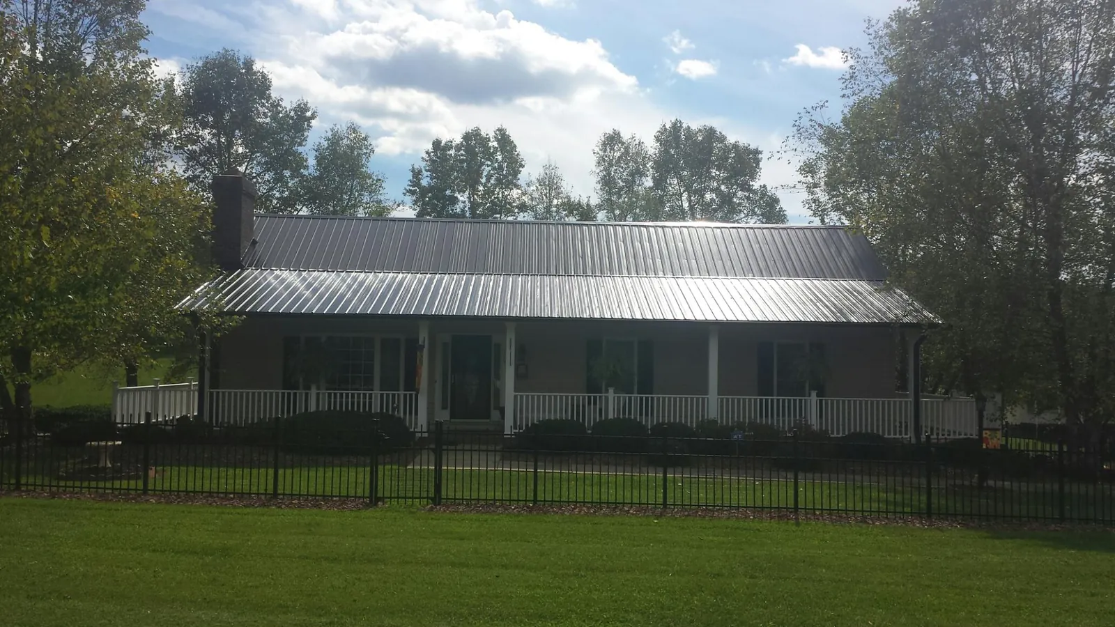 Gray metal roof on a brick ranch with a full width front porch — Gutter Guard Installation work by our crew in Pentwater