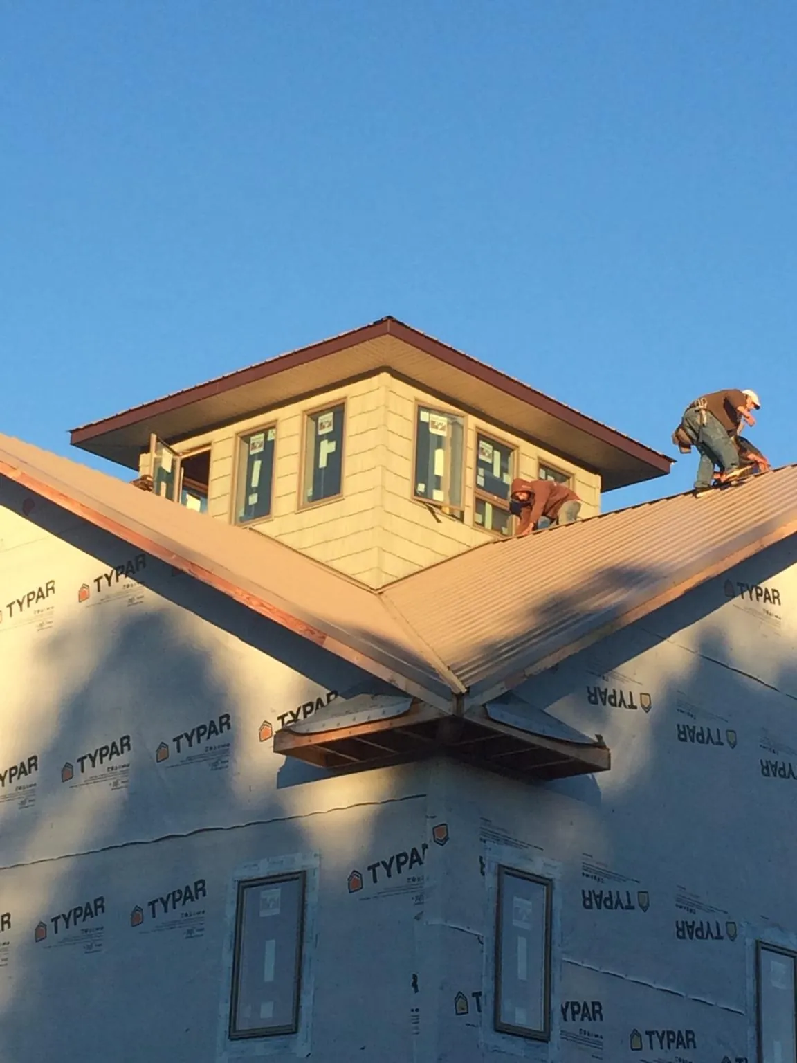 Roofers working around a rooftop cupola on a new metal roof at sunset — Roof Waterproofing in Pentwater by Roofing Brothers